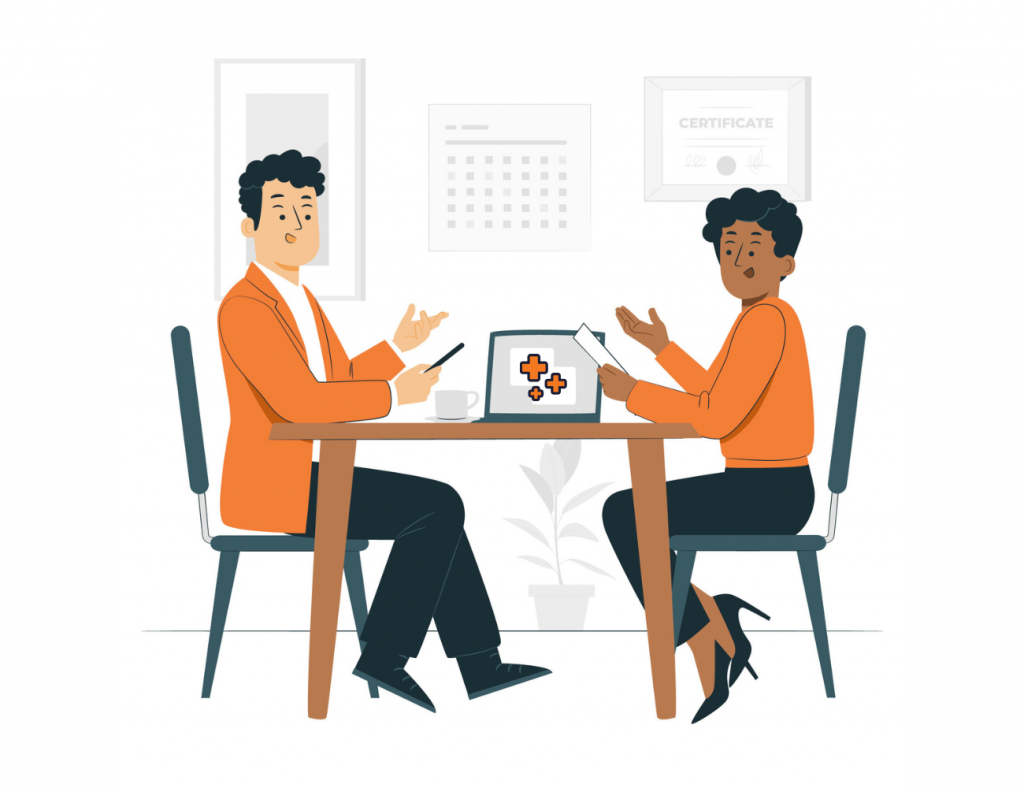 Two professionals seated at a table discussing wellness strategy. Both individuals appear engaged in conversation, representing a corporate wellness consultation.